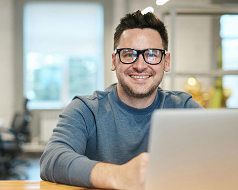 A stock image of a smiling man using a laptop